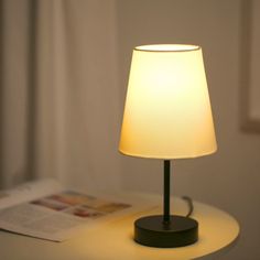 a lamp that is sitting on a table next to a book and some papers in front of it