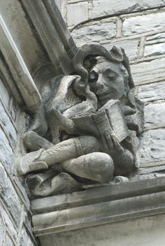 a statue of a man holding a book on the side of a building