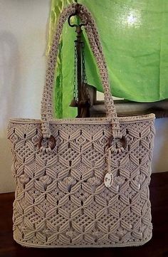 a crocheted bag sitting on top of a wooden table next to a green curtain