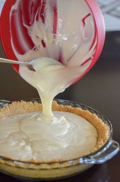 a person pouring white sauce on top of a pie