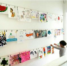 a young child is hanging pictures on the wall