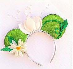 a green and white headband with flowers on the side, sitting on a table