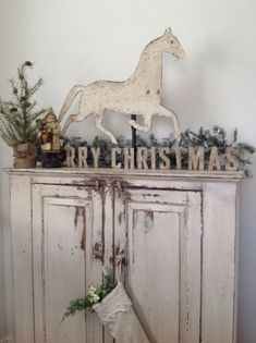 a white cabinet with a christmas stocking on top and a horse decoration above it