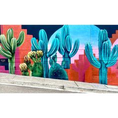 a mural on the side of a building with cactuses and other plants painted on it