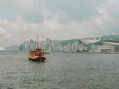 a yellow and red boat floating on top of a body of water next to tall buildings