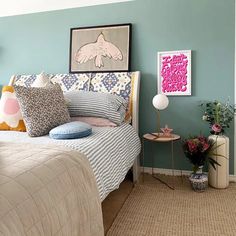 a bed room with a neatly made bed next to a table and flowers on the nightstand