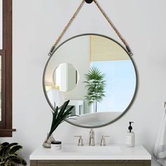 a bathroom with a round mirror hanging from the wall and a potted plant on the counter