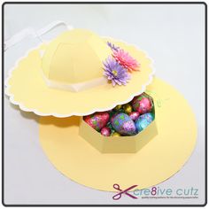 a paper hat with easter eggs in it on top of a yellow plate and white background