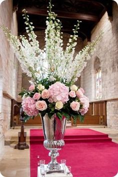 a vase filled with pink and white flowers on top of a red carpeted floor