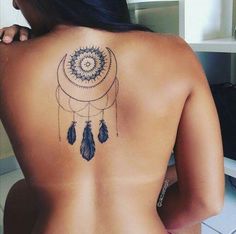 a woman with a tattoo on her back that has a dream catcher and feathers hanging from it