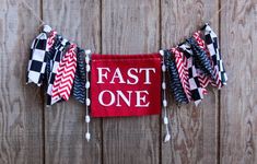 a red banner that says fast one hanging on a wooden fence with ribbons around it