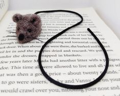 a small stuffed animal sitting on top of an open book next to a black string