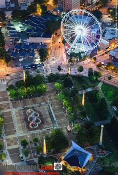 an aerial view of a ferris wheel in the middle of a city at night time