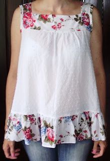 a woman standing in front of a door wearing jeans and a white top with flowers on it