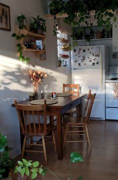 a kitchen with a table and chairs next to a refrigerator filled with potted plants