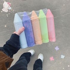 a person is holding several plastic bottles in front of their feet and the other hand is pointing at them