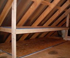 an attic with wooden flooring and exposed rafters on the walls, in need of remodel