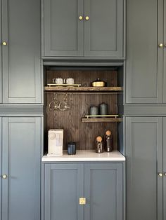 a kitchen with gray cupboards and white counter tops, gold pulls on the doors