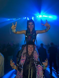 a woman sitting on top of a man in front of a crowd at a concert