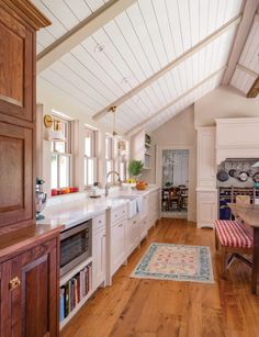 a large kitchen with wooden floors and white cabinetry, along with an area rug on the floor