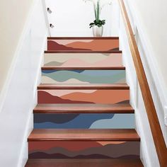 a set of stairs painted with different colors and designs on the riser, along with a potted plant