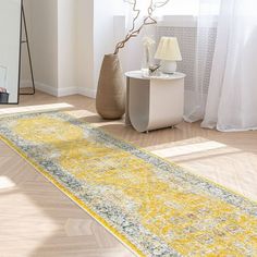 a yellow and gray rug on the floor in front of a mirror with a vase next to it