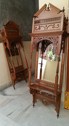 two wooden mirrors sitting next to each other on the ground in front of a wall