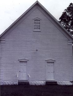 an old white church building with two doors