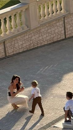 a woman kneeling down next to a little boy