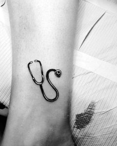 a black and white photo of a stethoscope tattoo on the ankle