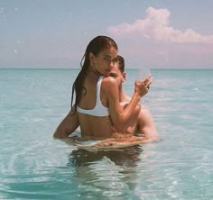 two people sitting in the ocean drinking wine