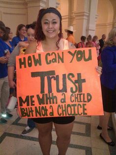 a woman holding a sign that says, how can you trust me with a child but not a choice?