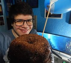 a man holding a chocolate cake with a toothpick sticking out of it