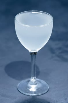 a wine glass sitting on top of a blue tablecloth covered floor with a black background