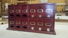 a wooden cabinet with many drawers and knobs on the front, in a workshop