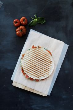 a grilled sandwich sitting on top of a napkin next to tomatoes