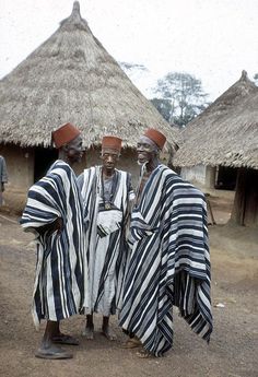 three african men standing next to each other in front of thatched roof huts with grass roofs