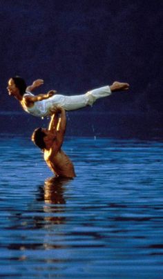 two people doing tricks in the water with their hands up and one person upside down