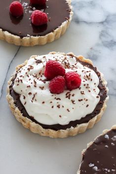 three chocolate tarts with raspberries on top