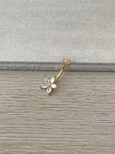 a gold flower brooch sitting on top of a wooden floor next to a wall