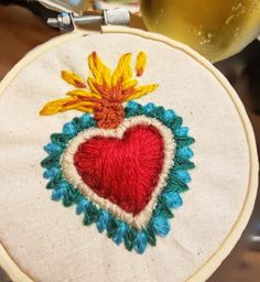 an embroidered heart on a hoop with a glass of wine in the backgroud