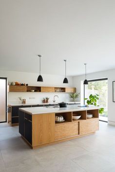 an open kitchen with wooden cabinets and black pendant lights hanging from the ceiling over the island