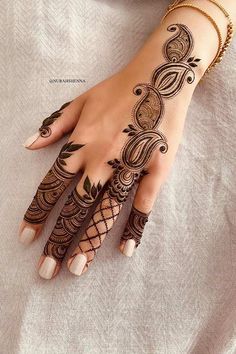 a woman's hand with henna tattoos on it, and her hands are decorated with