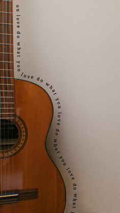 an acoustic guitar sitting on top of a white wall