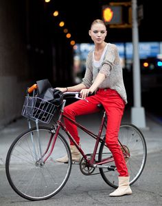 a woman in red pants is riding a bike