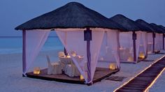 a row of gazebos on the beach with candles lit up in front of them