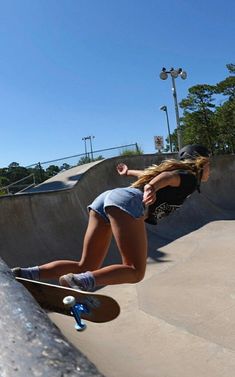 a young woman riding a skateboard up the side of a cement ramp at a skate park