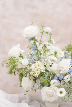 a vase filled with white and blue flowers on top of a tablecloth covered floor