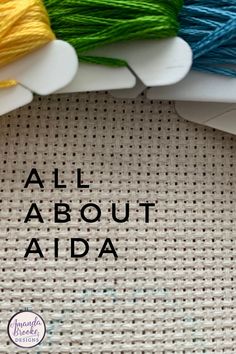 the words all about aida are written in black on a white background with multicolored spools of thread