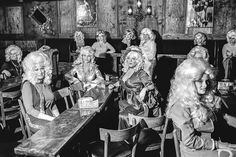 black and white photograph of women sitting at wooden tables with long blonde hair on them